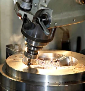 The image shows a CNC machine tool cutting a metal workpiece with sparks and shavings flying off